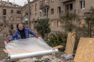 L'homme se prépare à monter les fenêtres d'une maison endommagée par le feu à Kostiantinibuka dans la région de Donetsk orientale